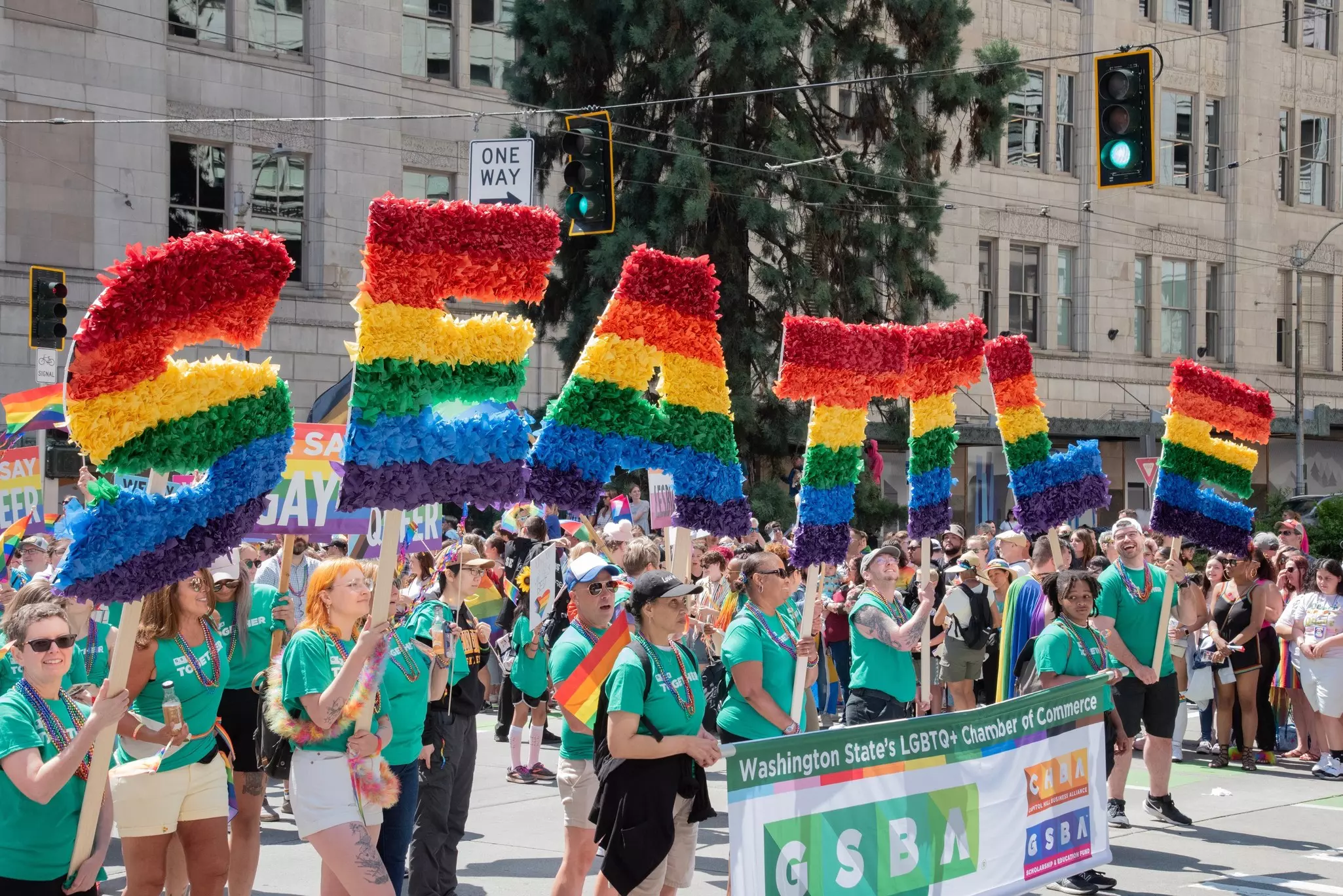 Marchers carry rainbow balloons spelling out SEATTLE at a Pride parade