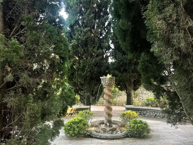 A fountain in the center of a patio in a garden.