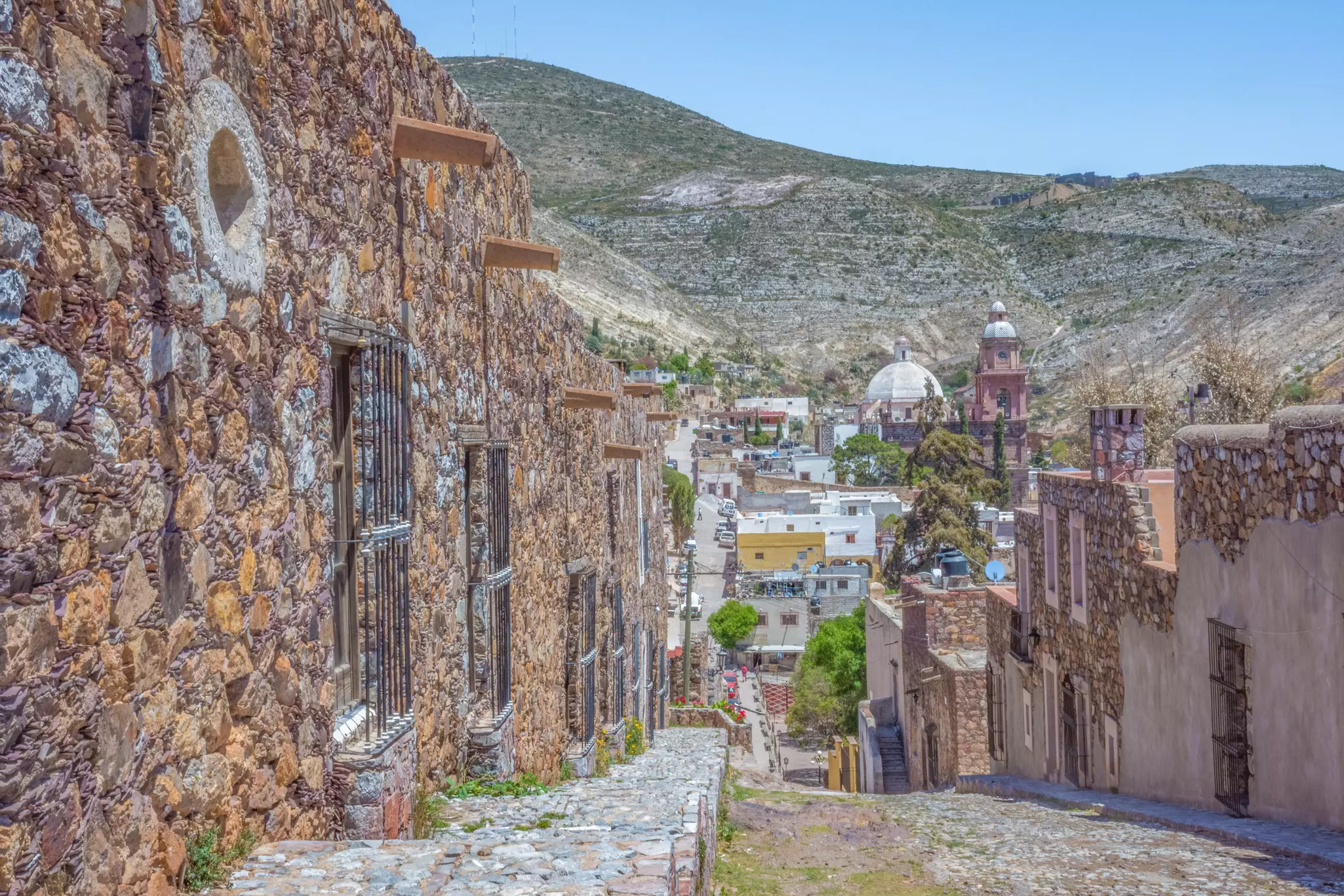 Cobbled streets and stone buildings in an abandoned mining zone at the edge of a hill town.