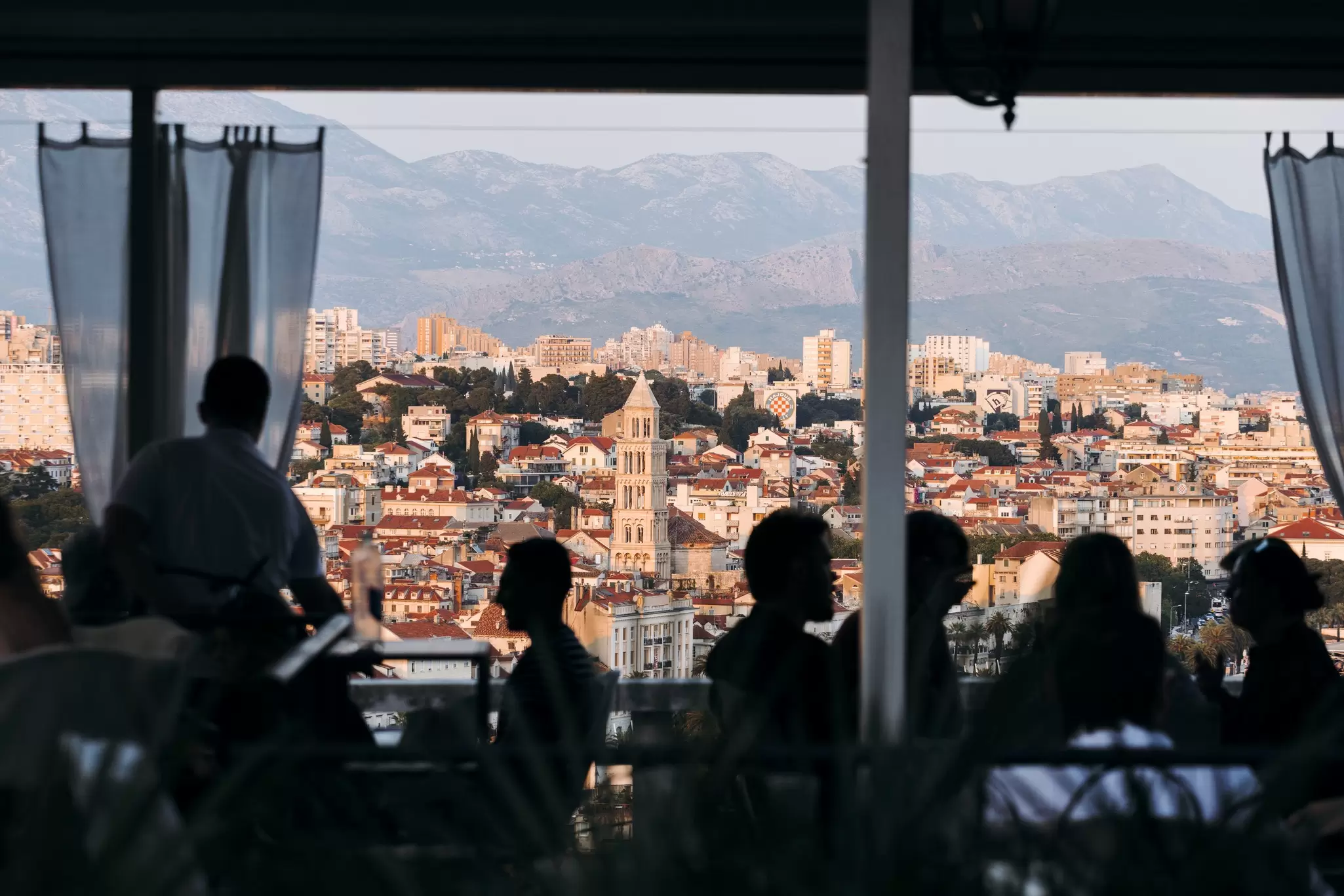 Diners silohuetted by the sunset, a view of Split at sunset from a restaurant at Marjan Hill