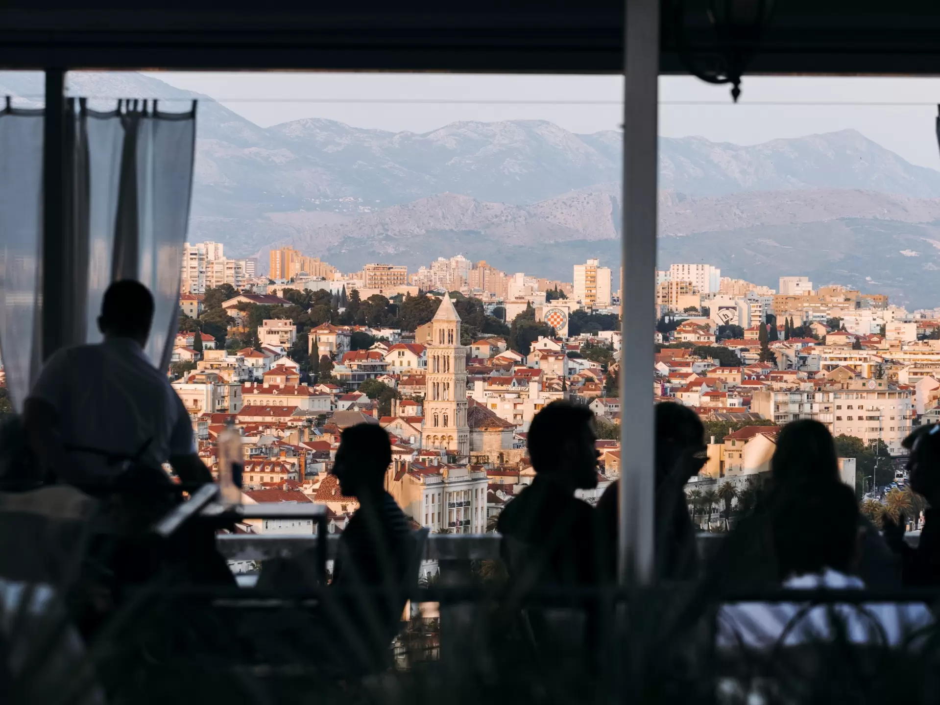 Diners silohuetted by the sunset, a view of Split at sunset from a restaurant at Marjan Hill