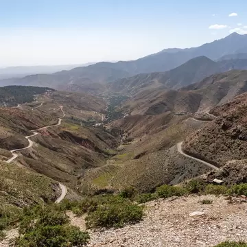 a road winds through mountains that are mostly green and also brown