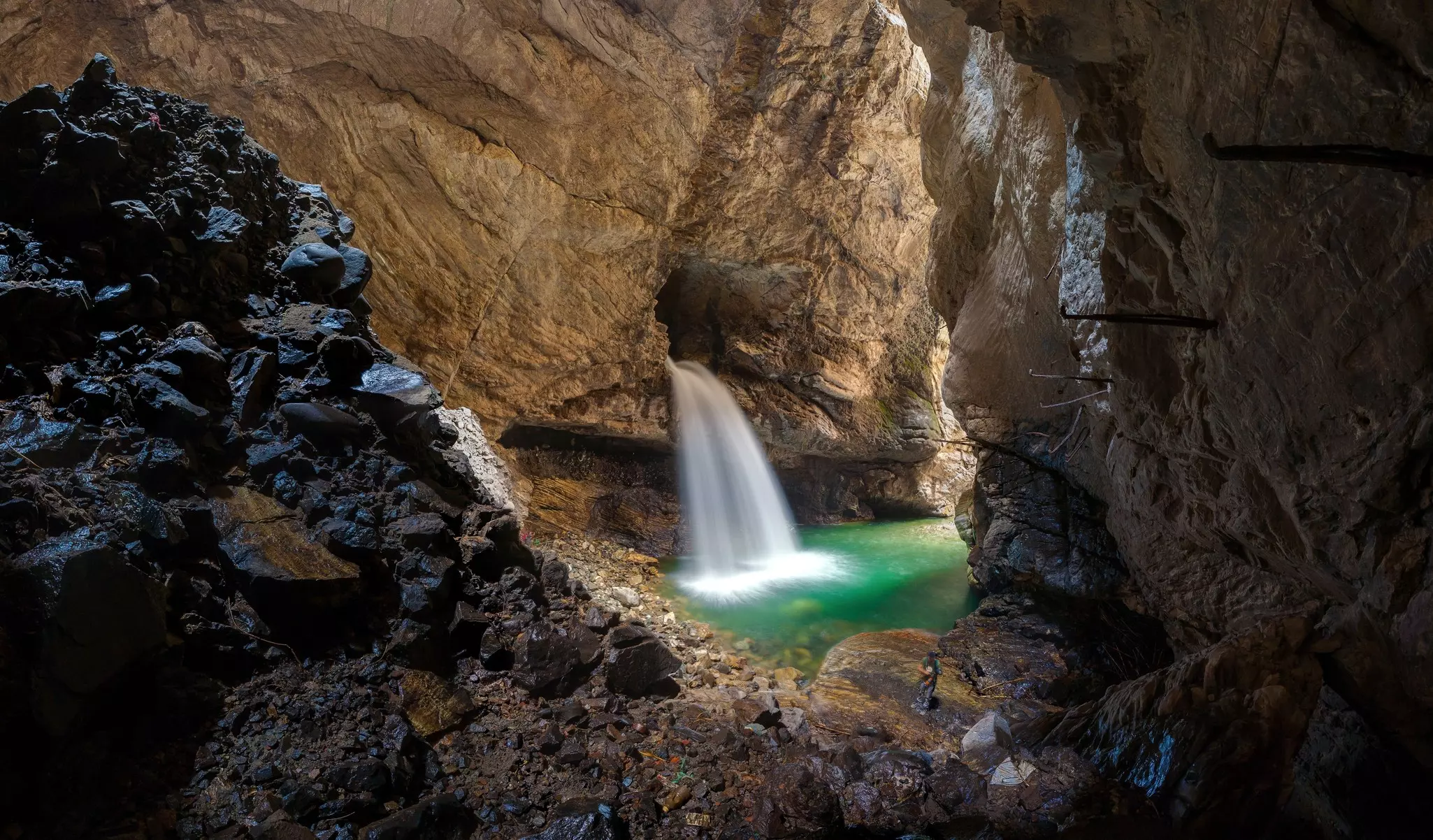 A waterfall emerges from a rock in a canyon formation