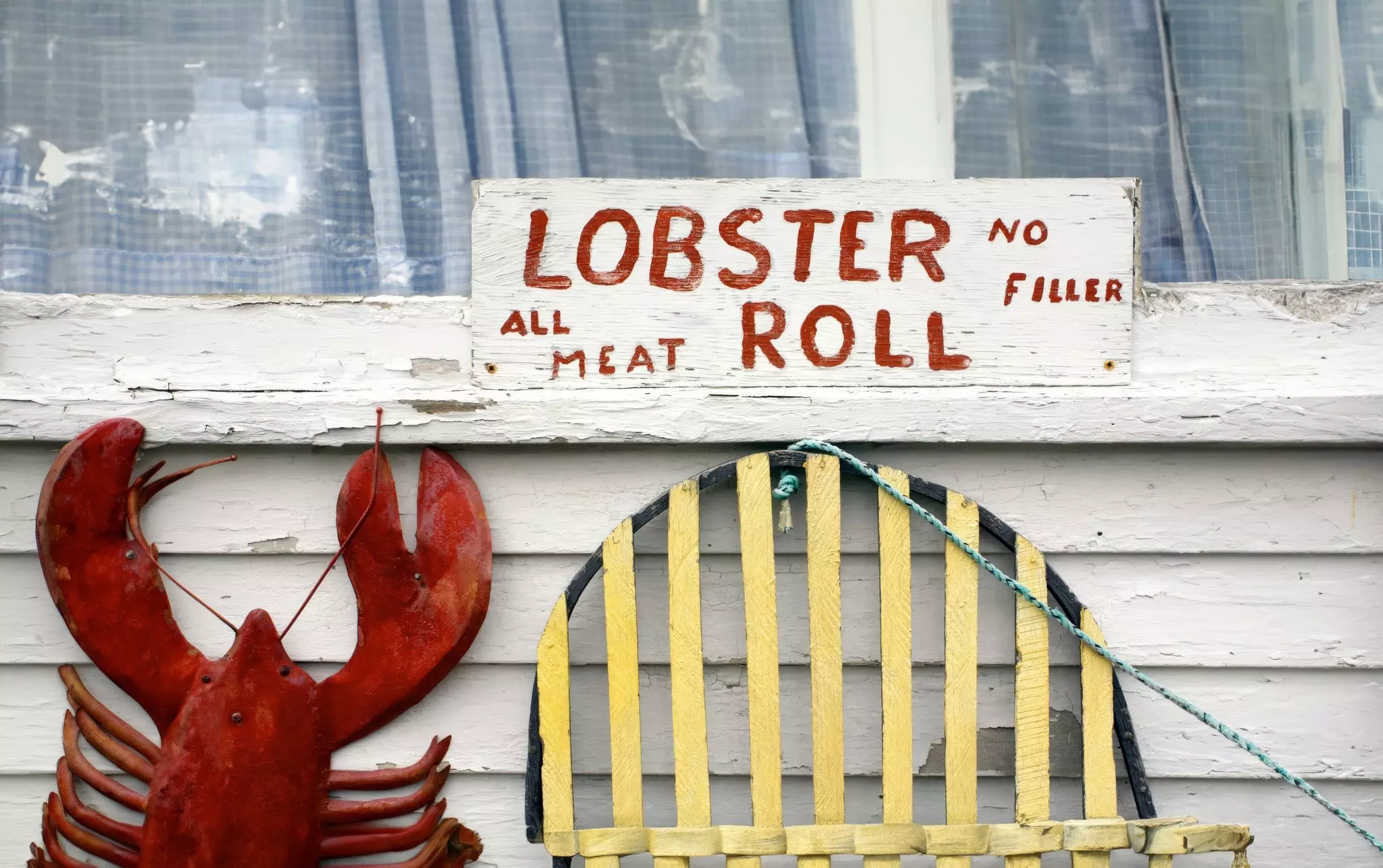 A sign advertising lobster rolls depicts a lobster on the exterior of a seafood shack.