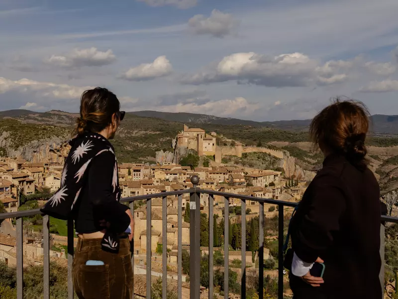 Two people stand at a railing looking out a historic town.