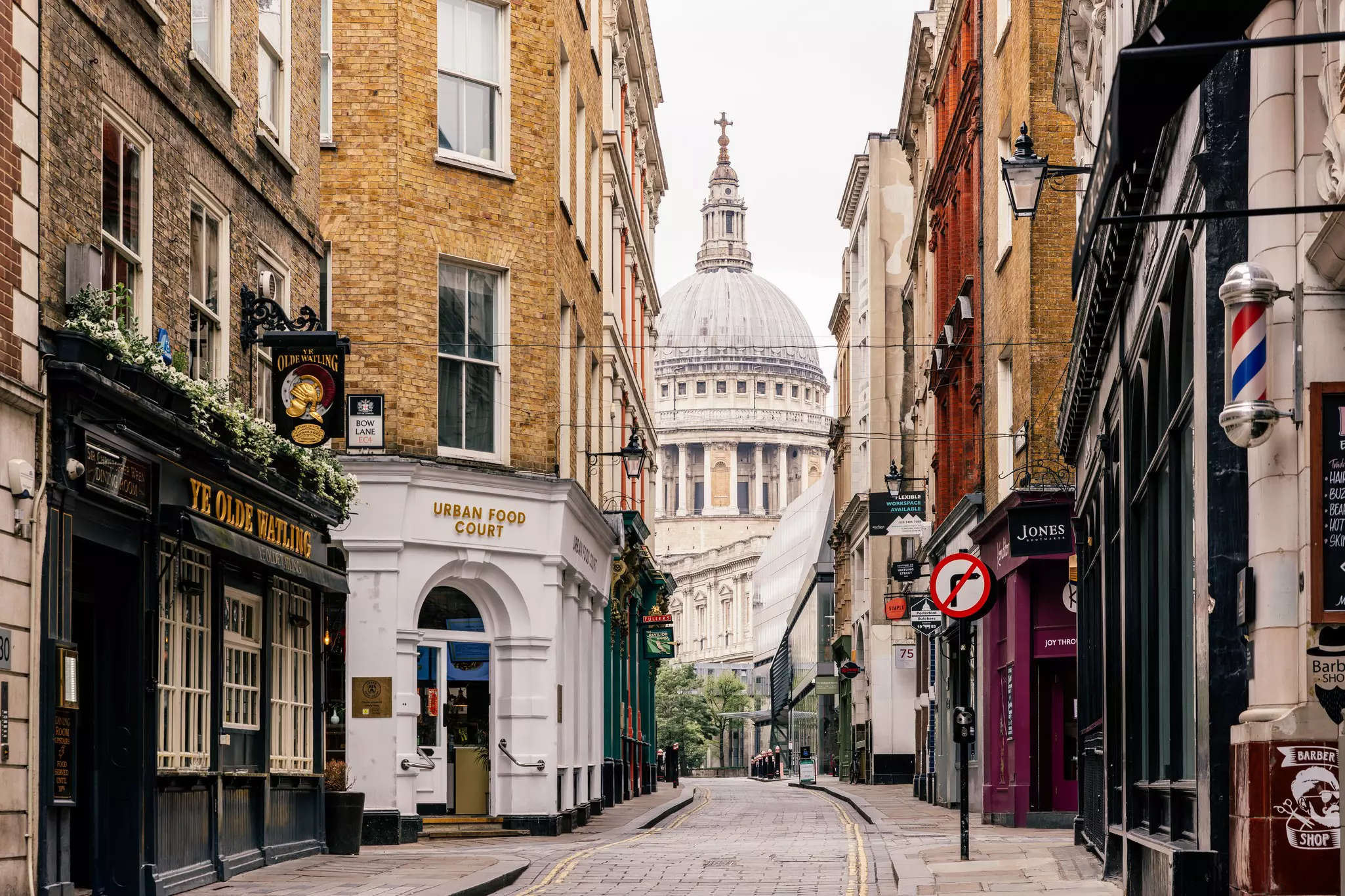 A view of St Paul's Cathedral at the top of a narrow street in London. 