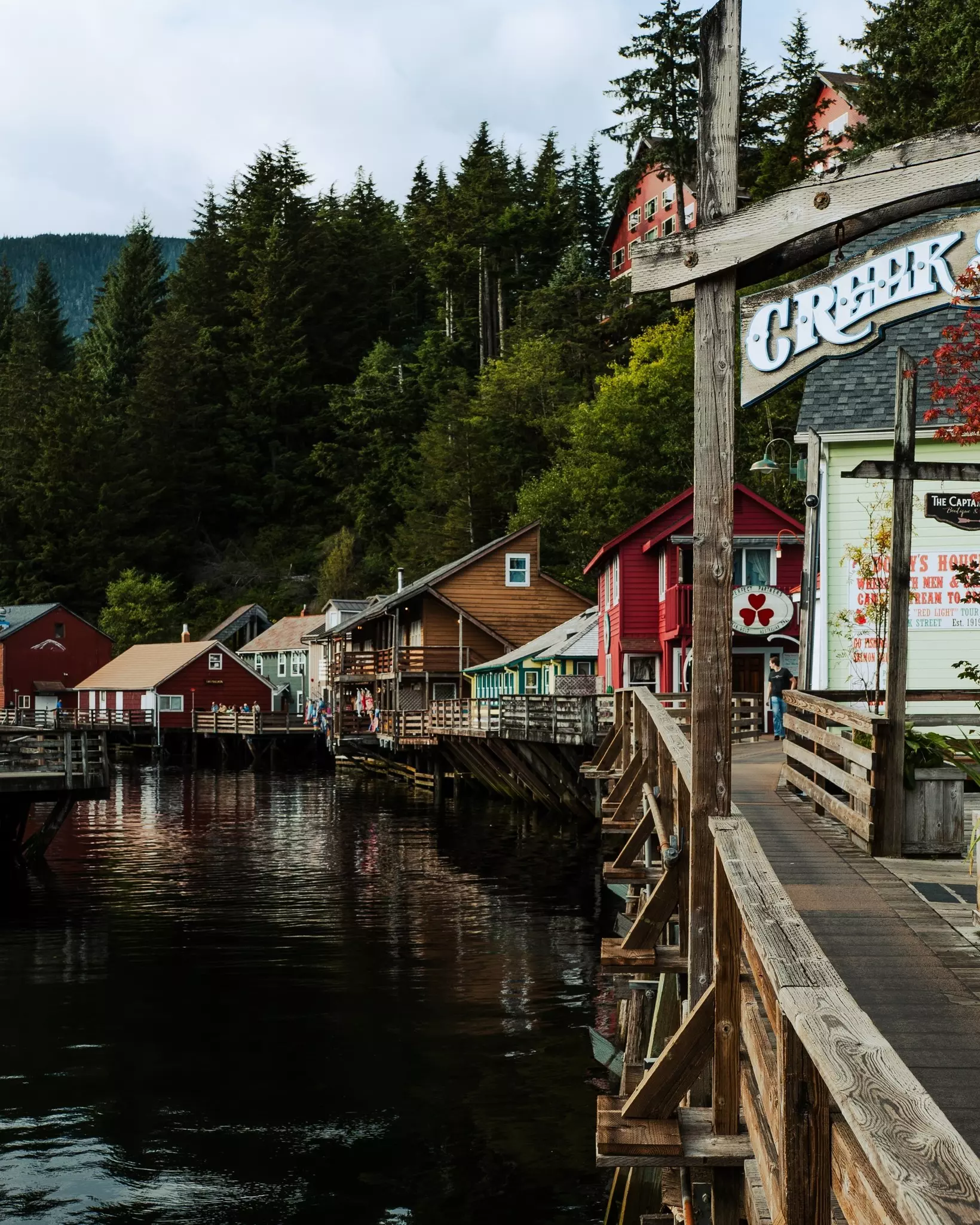 A wooden boardwalk in front of harborfront homes and shops on a sunny day