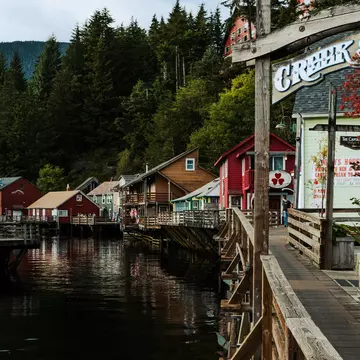 A wooden boardwalk in front of harborfront homes and shops on a sunny day