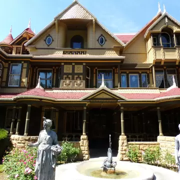 April 2, 2016: Exterior of the Winchester Mystery House with statues and a fountain.
