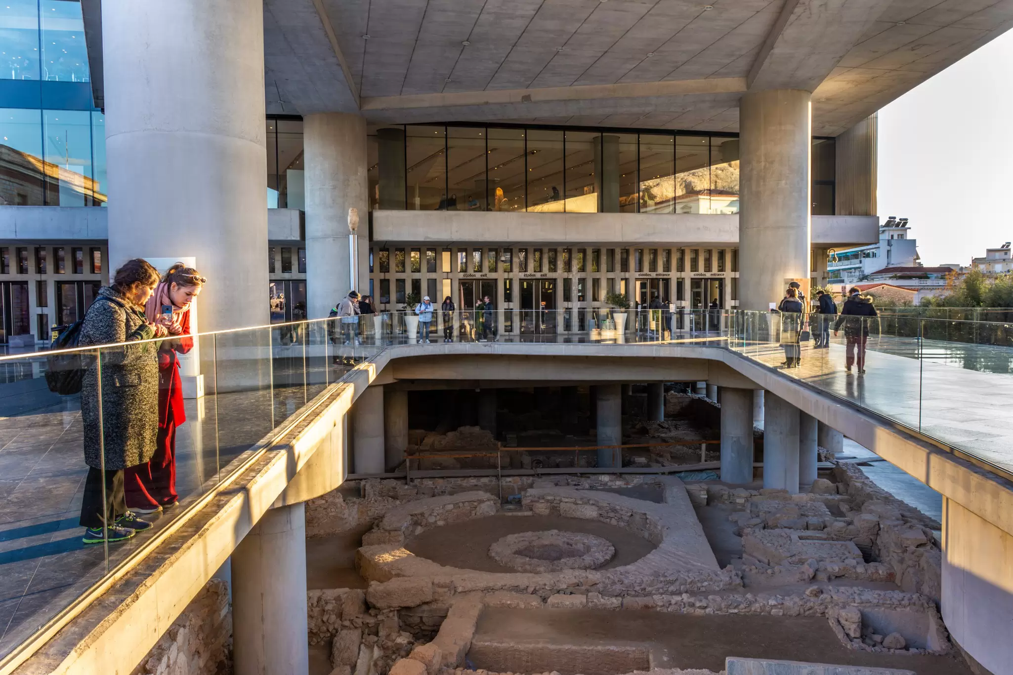 Tourist look down at the ruins at the entrance of the Acropolis Museum in Athens, Greece.