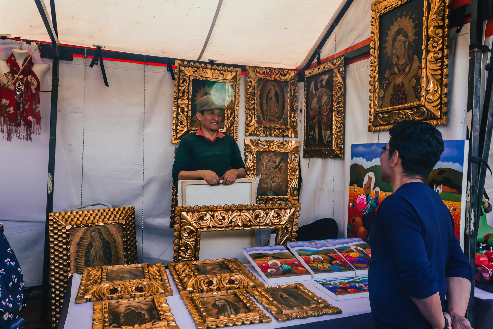 A vendor at a stand with carved gold frames.