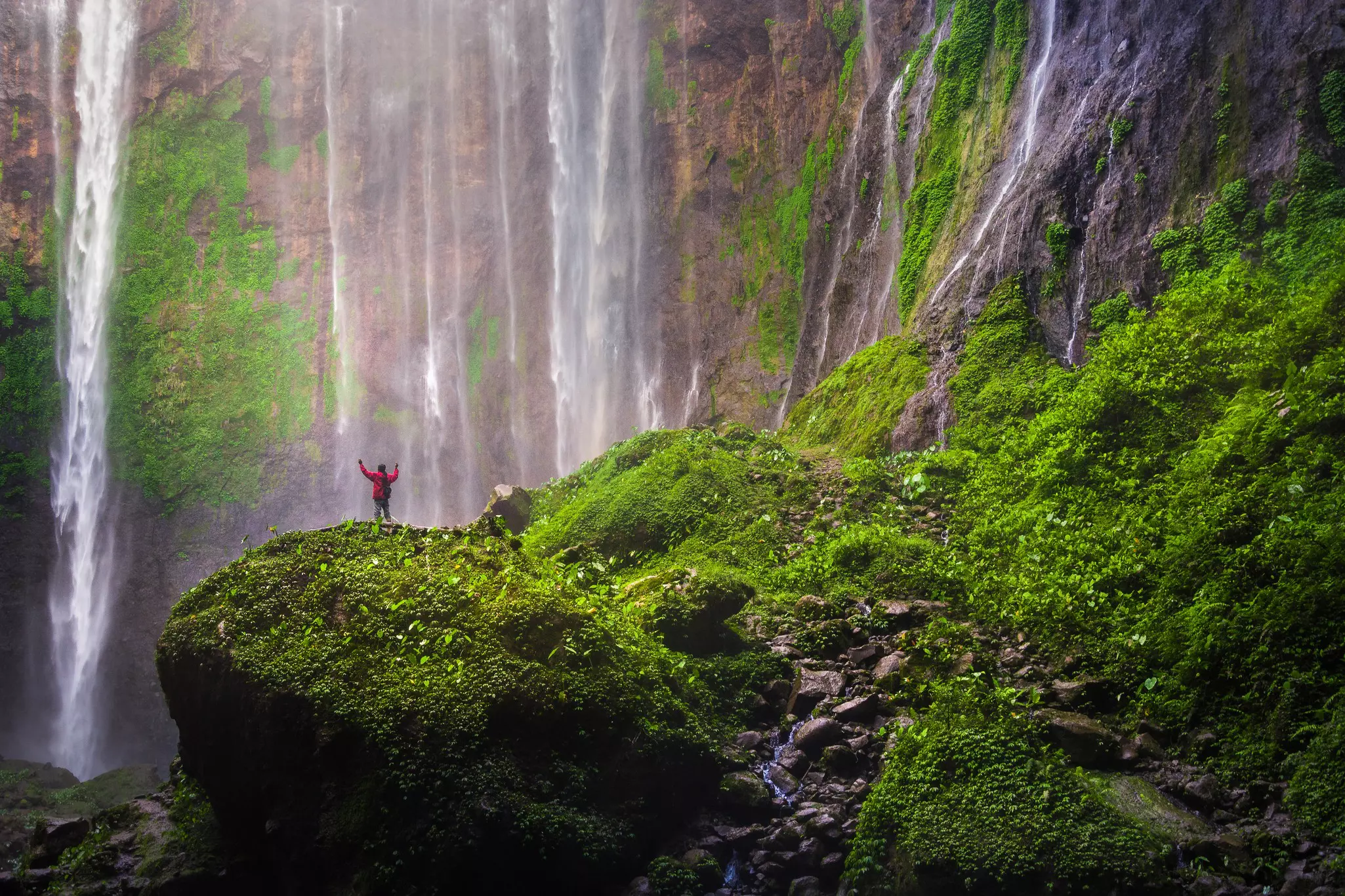A man standing on the rocks at Tumpak Sewu waterfall, East Java, Indonesia.