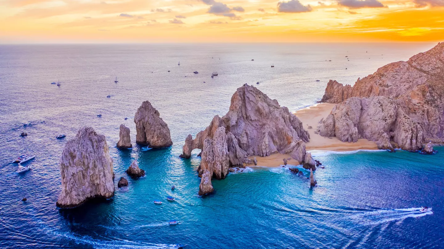 Aerial view of boats speeding by El Arco de Cabo San Lucas, Mexico at sunset