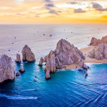 Aerial view of boats speeding by El Arco de Cabo San Lucas, Mexico at sunset