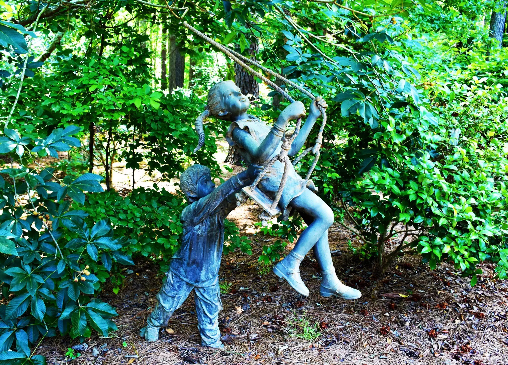 Statue of a young boy pushing a young girl on a swing at the Cape Fear Botanical Garden in Fayetteville, North Carolina.