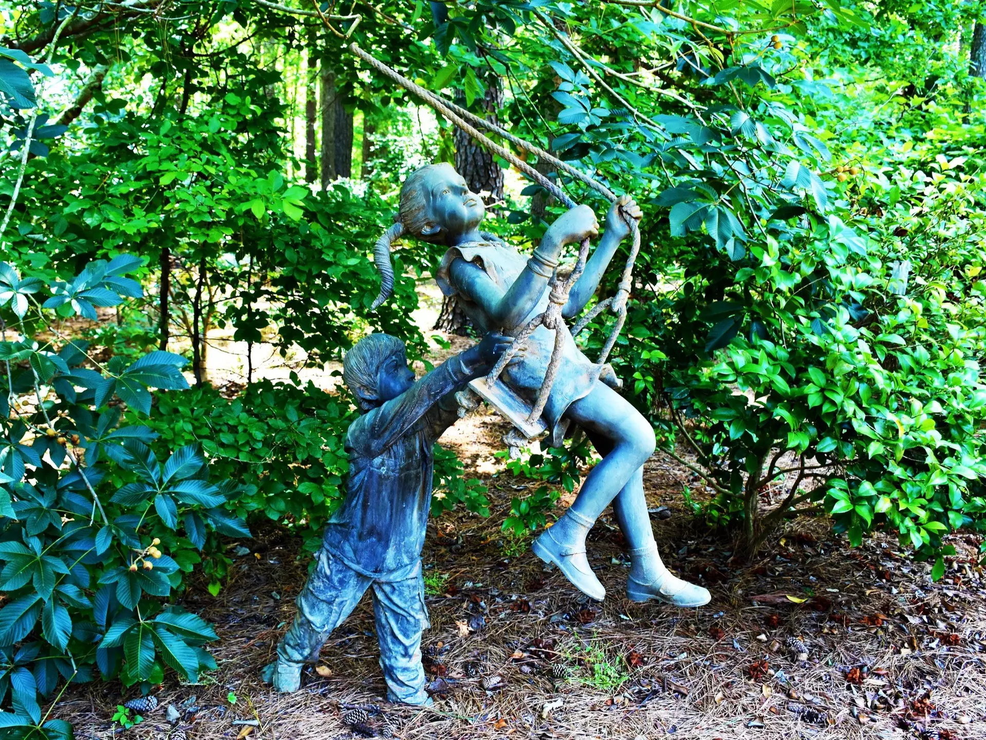 Statue of a young boy pushing a young girl on a swing at the Cape Fear Botanical Garden in Fayetteville, North Carolina.