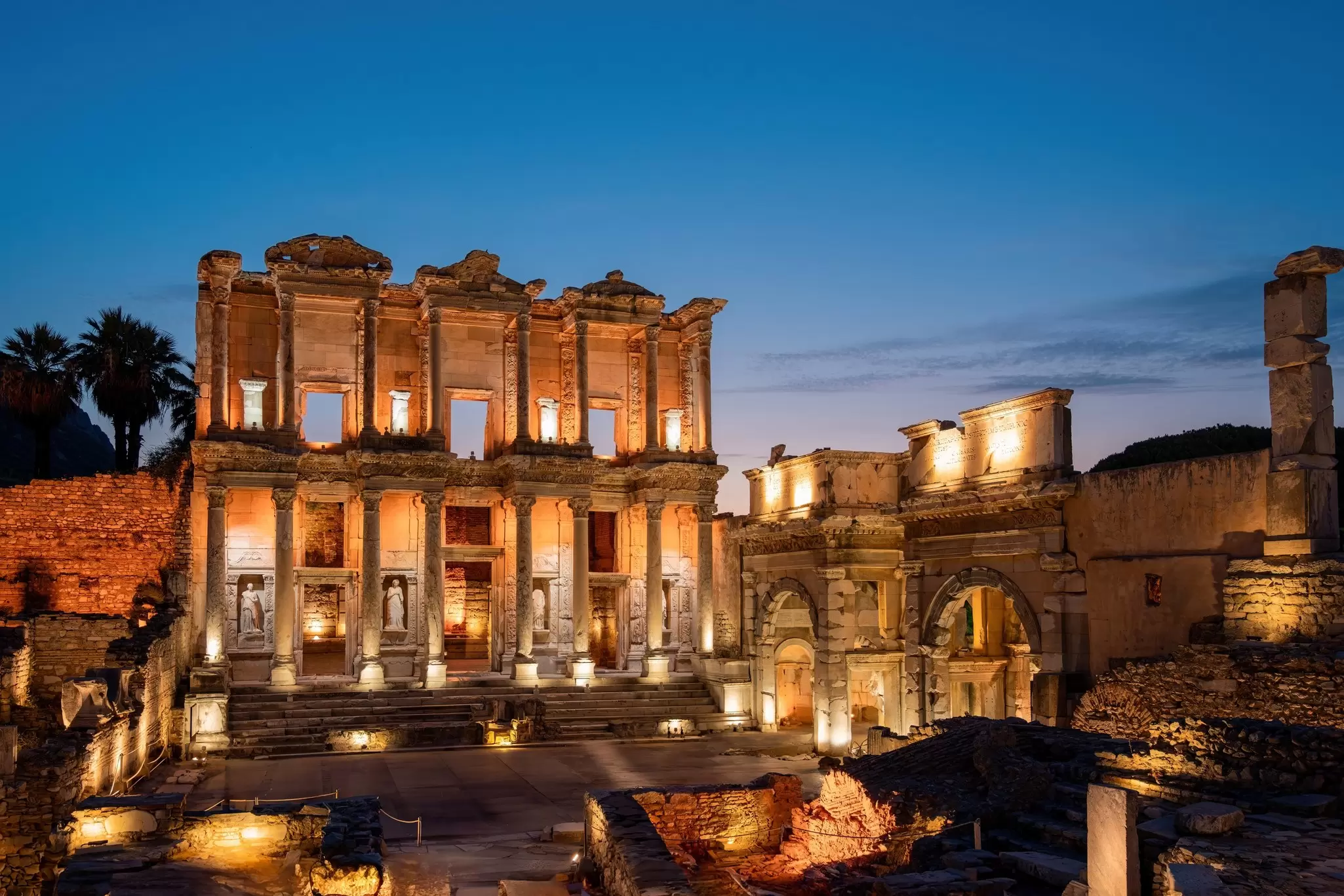 Ancient ruins lit up at night, with a columned frontage to a tall sandstone facade at Ephesus in Turkey
