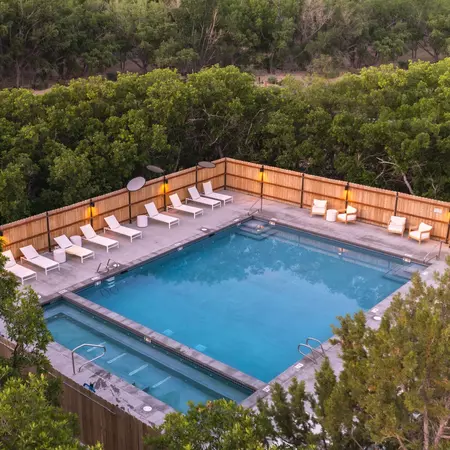 Square pool surrounded by lawn chairs with a canyon in the background