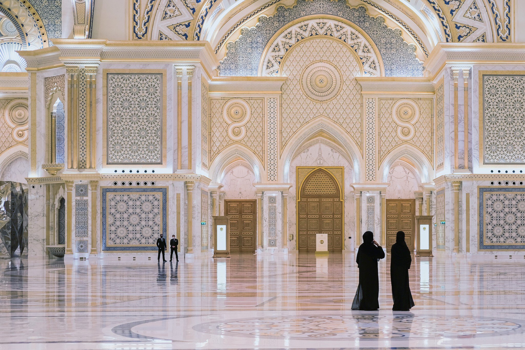 Abu Dhabi,UAE, March 2021.Two arabian local woman dressed traditional black visiting The Great Hall of new majestic Presidential Palace, Qasr Al Watan,with security guard team on blurred background., License Type: media, Download Time: 2025-11-26T15:13:44.000Z, User: clairenaylor, Editorial: true, purchase_order: 65050 - Digital Destinations and Articles, job: Online editorial, client: Abu Dhabi things to know, other: Claire Naylor