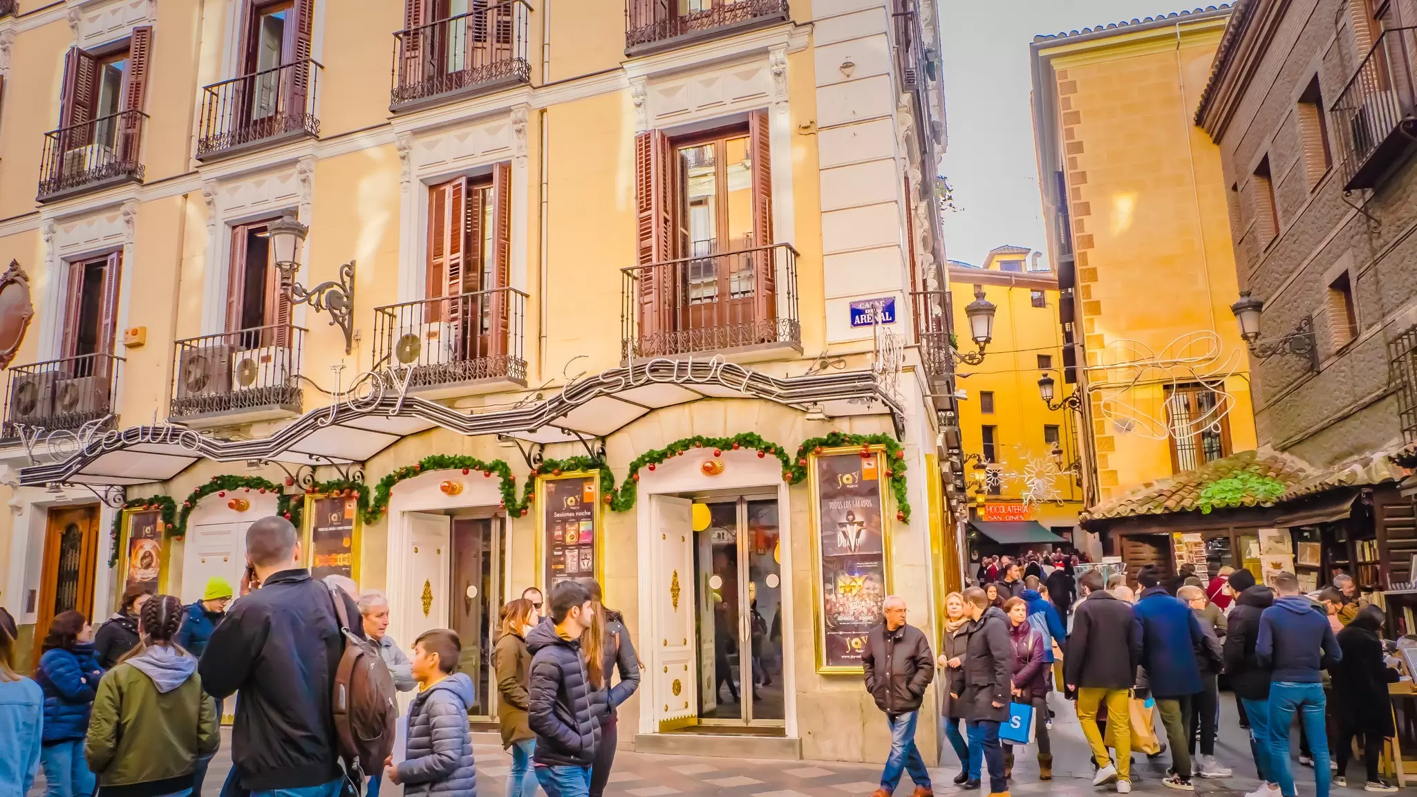 Christmas decorations on the exterior of a theater as people in heavy coats walk past.