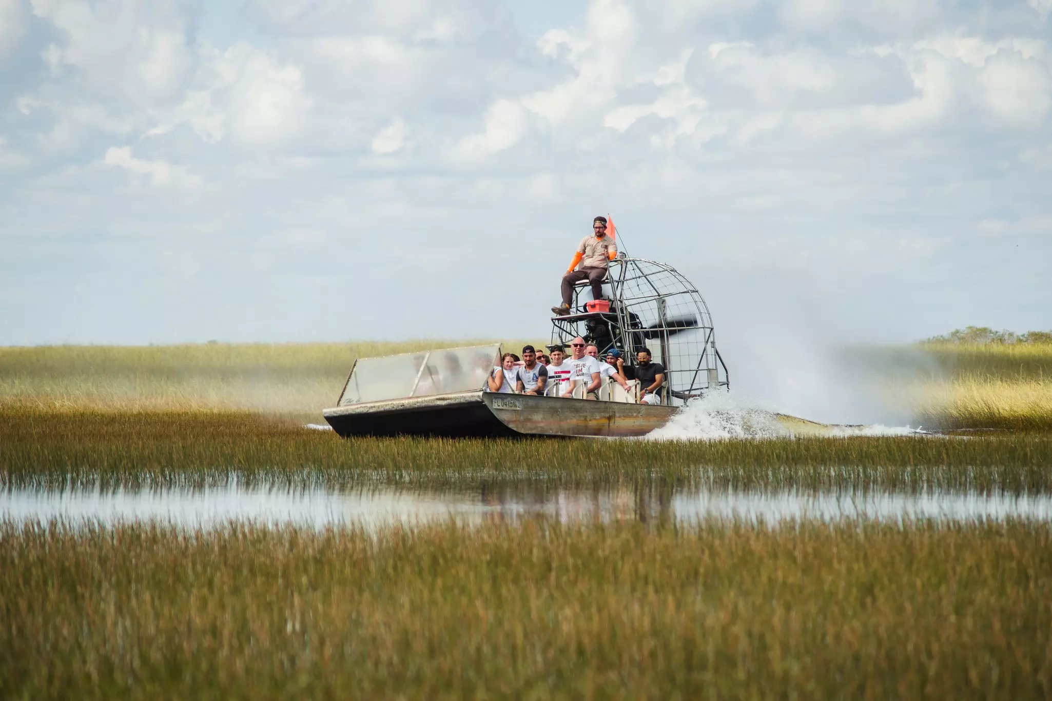Tourists on an airboat speeding over flooded grassland in Everglades National Park, Florida, USA.