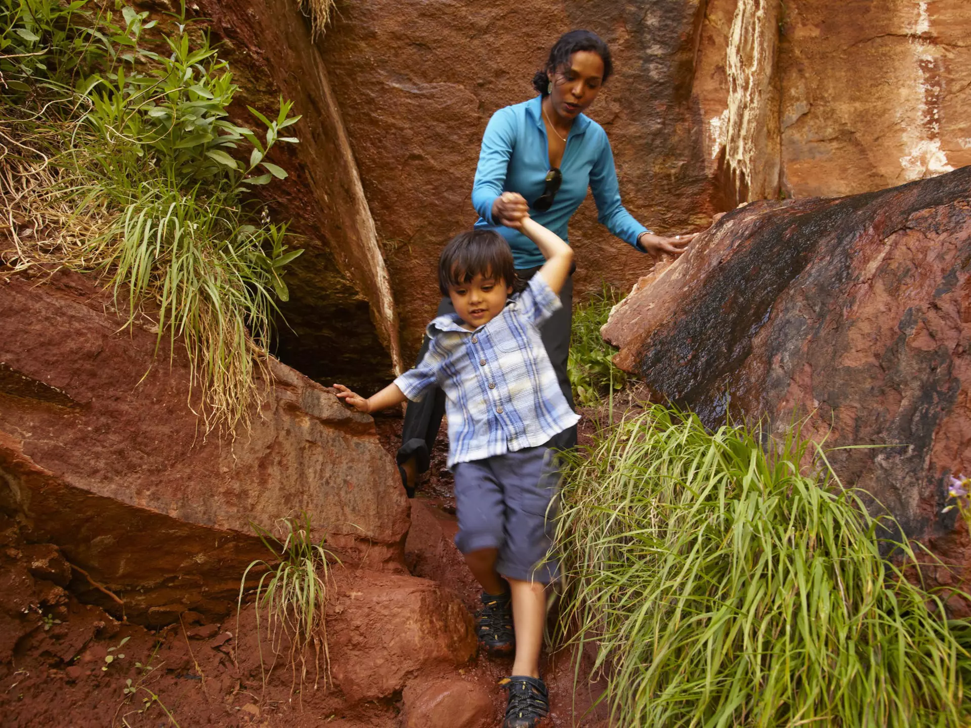 Mother helping son climb down rocks