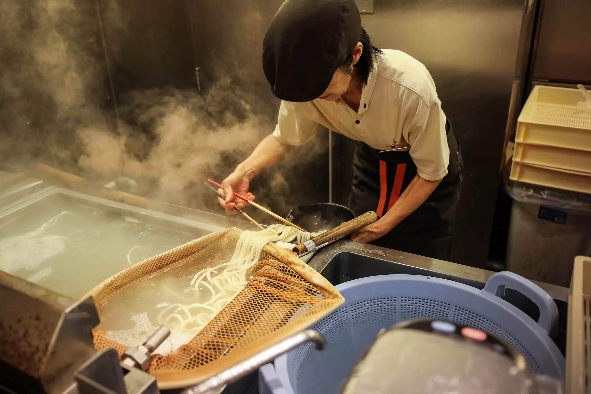 A chef preparing noodles for ramen in a restaurant kitchen in Osaka