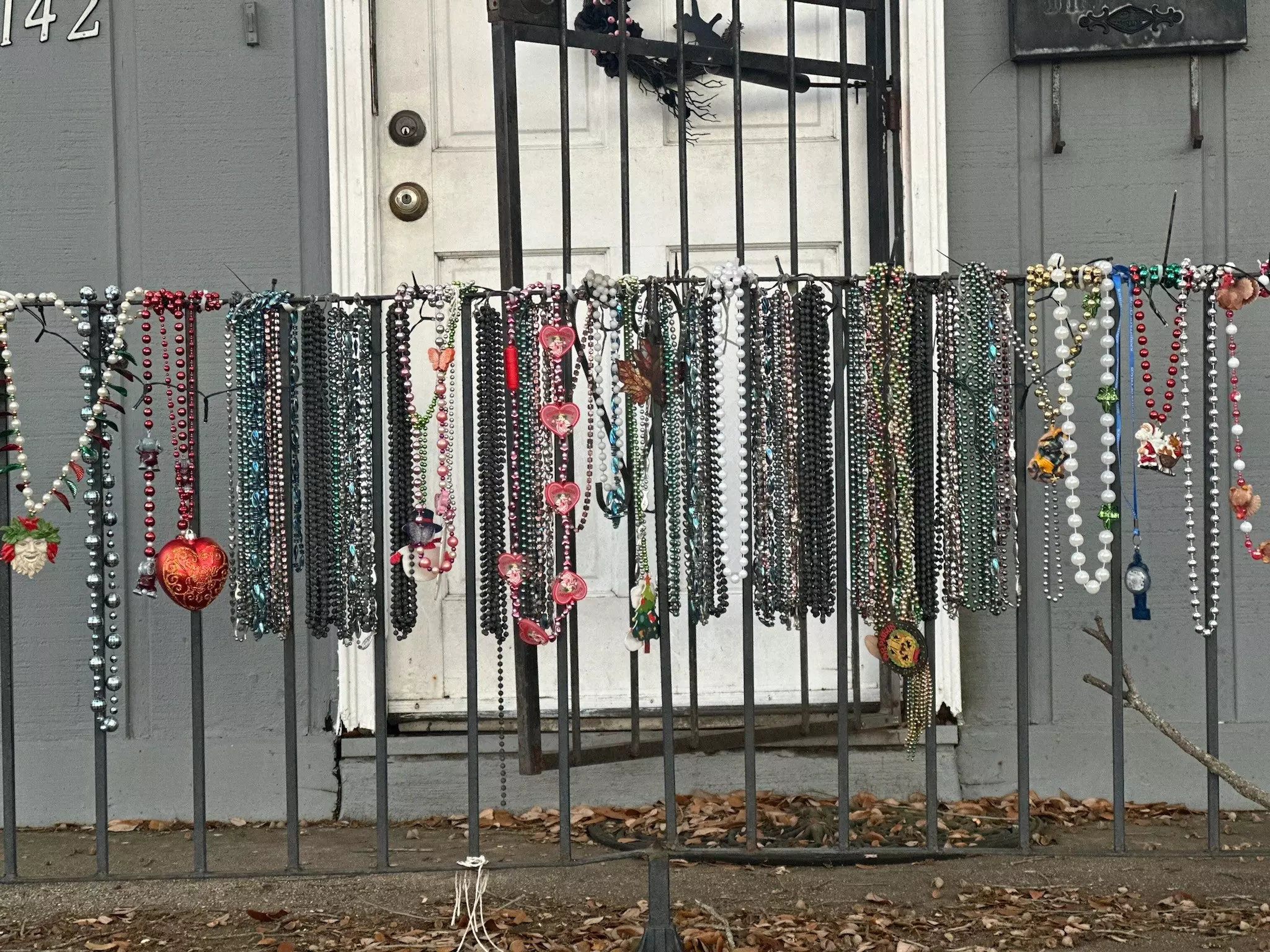 Necklaces of beads hanging from a wrought iron fence.