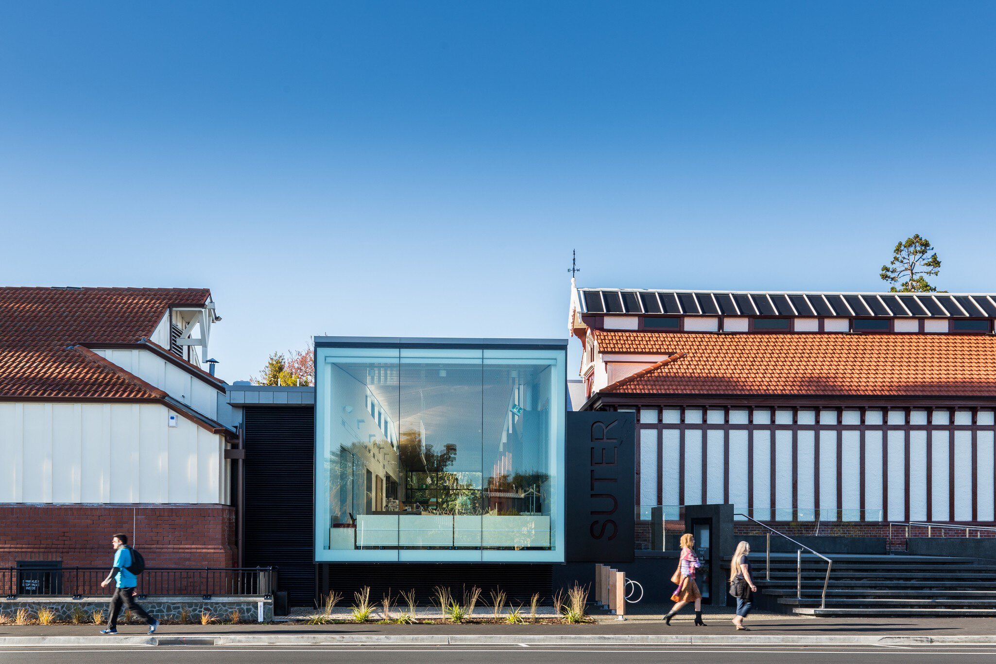 Exterior of Suter Art Gallery in Nelson, New Zealand. Pedestrians walking in front, blue sky above.