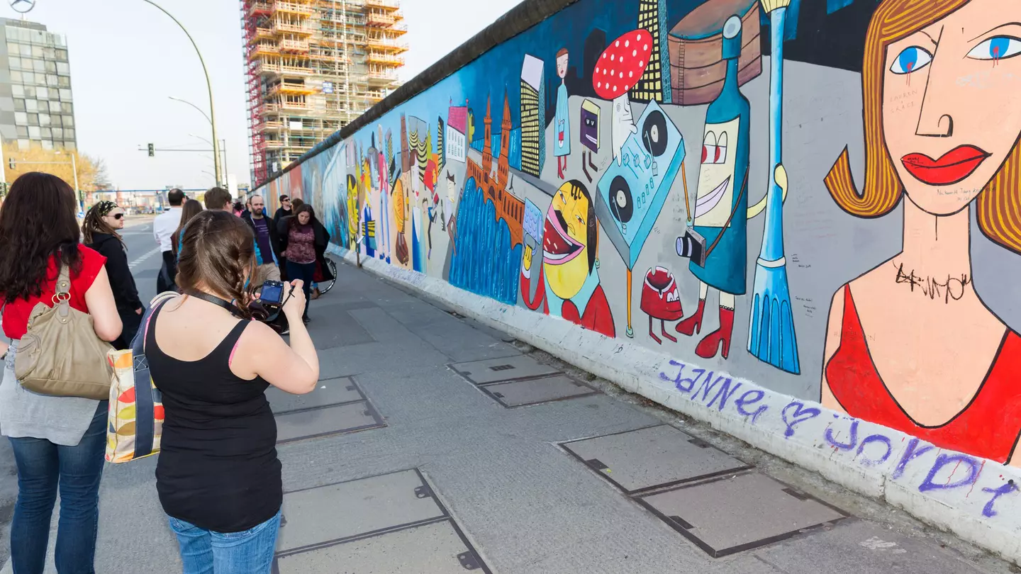 Girl looks over a barrier at a penguin staring back up at her © Sarah Stocking / Lonely Planet