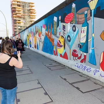 Girl looks over a barrier at a penguin staring back up at her © Sarah Stocking / Lonely Planet