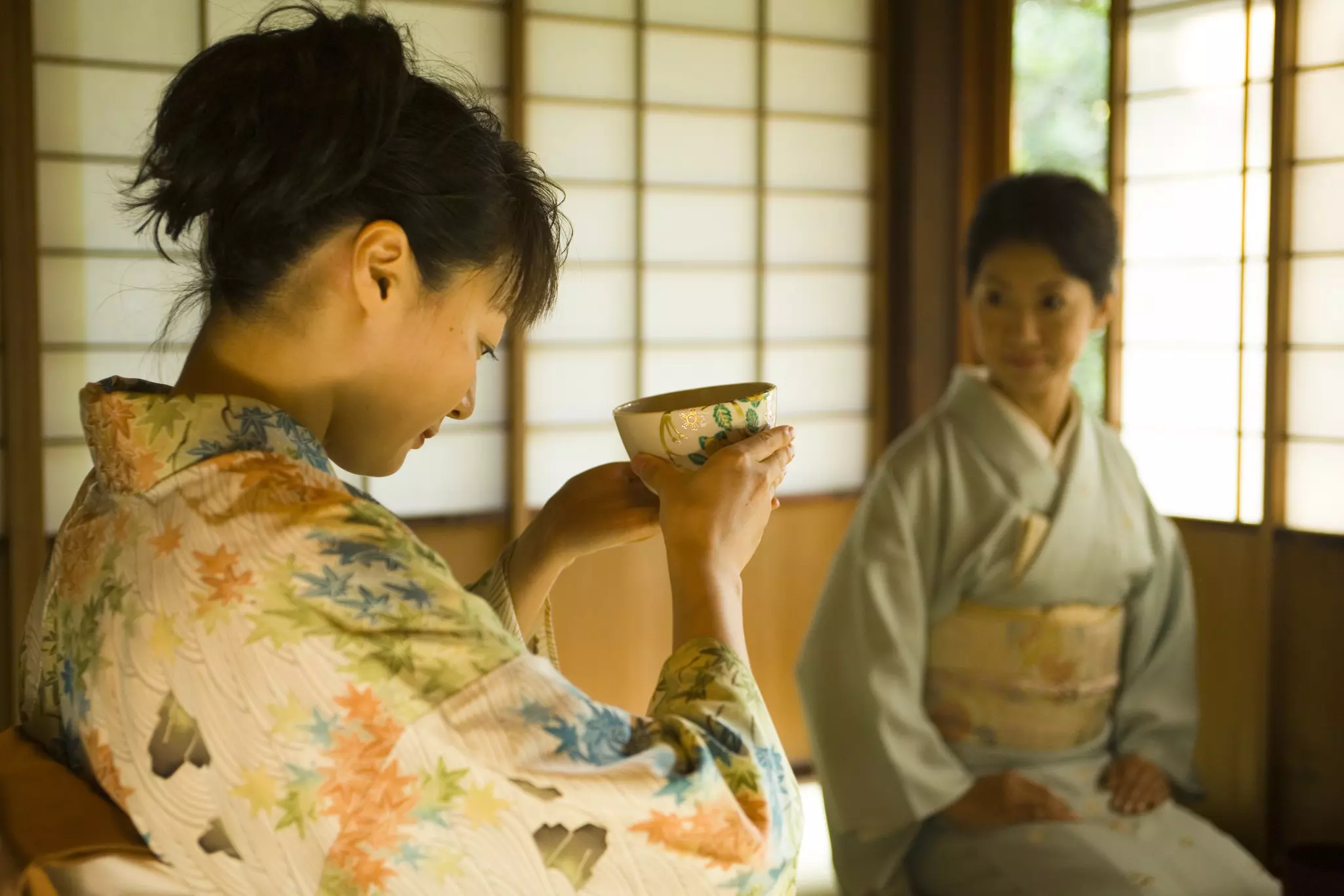 Two women in kimono take part in a tea ceremony