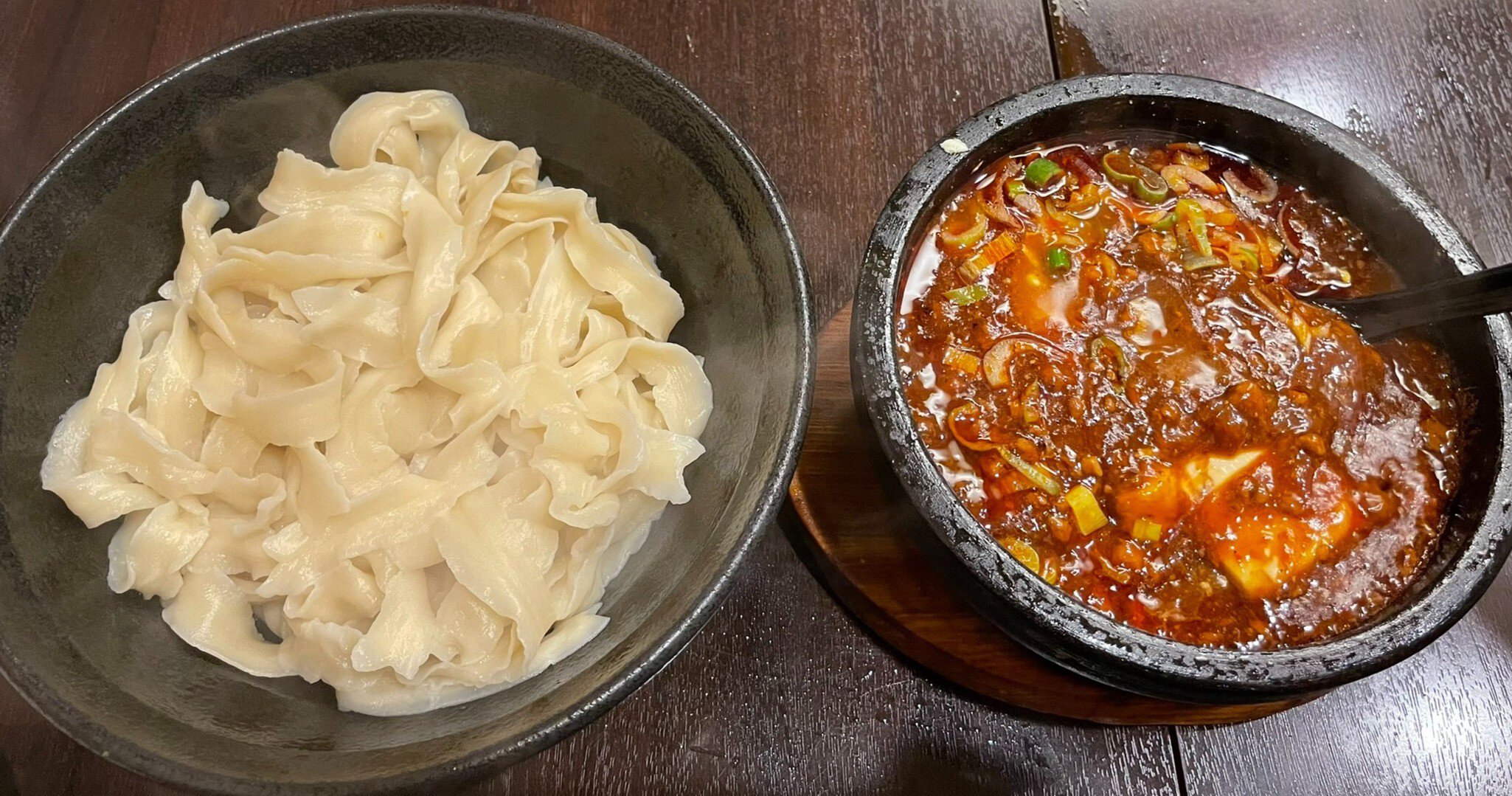 A bowl of pale noodles next to a bowl of reddish mapo dofu
