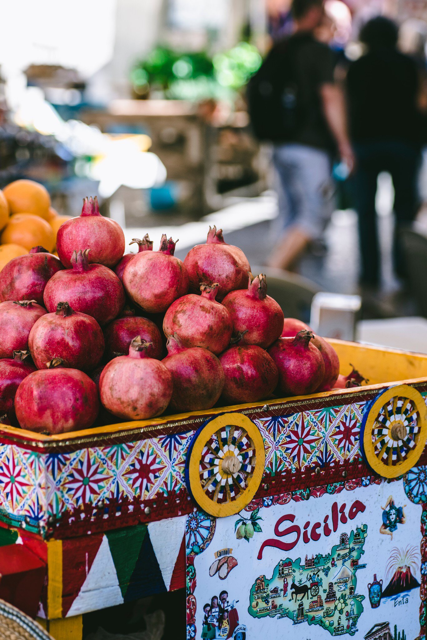  Ripe pomegranates in a brightly colored bin at an outdoor market.