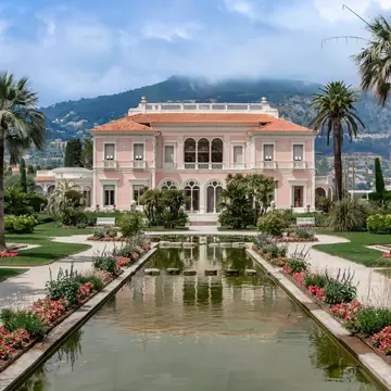 Villa Ephrussi de Rothschild in Saint-Jean-Cap-Ferrat, France. French Riviera. Beautiful gardens and a tranquil water feature set against scenic mountains.