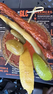 A well-garnished cocktail served with lemon, lime, an olive, gherkin and meat