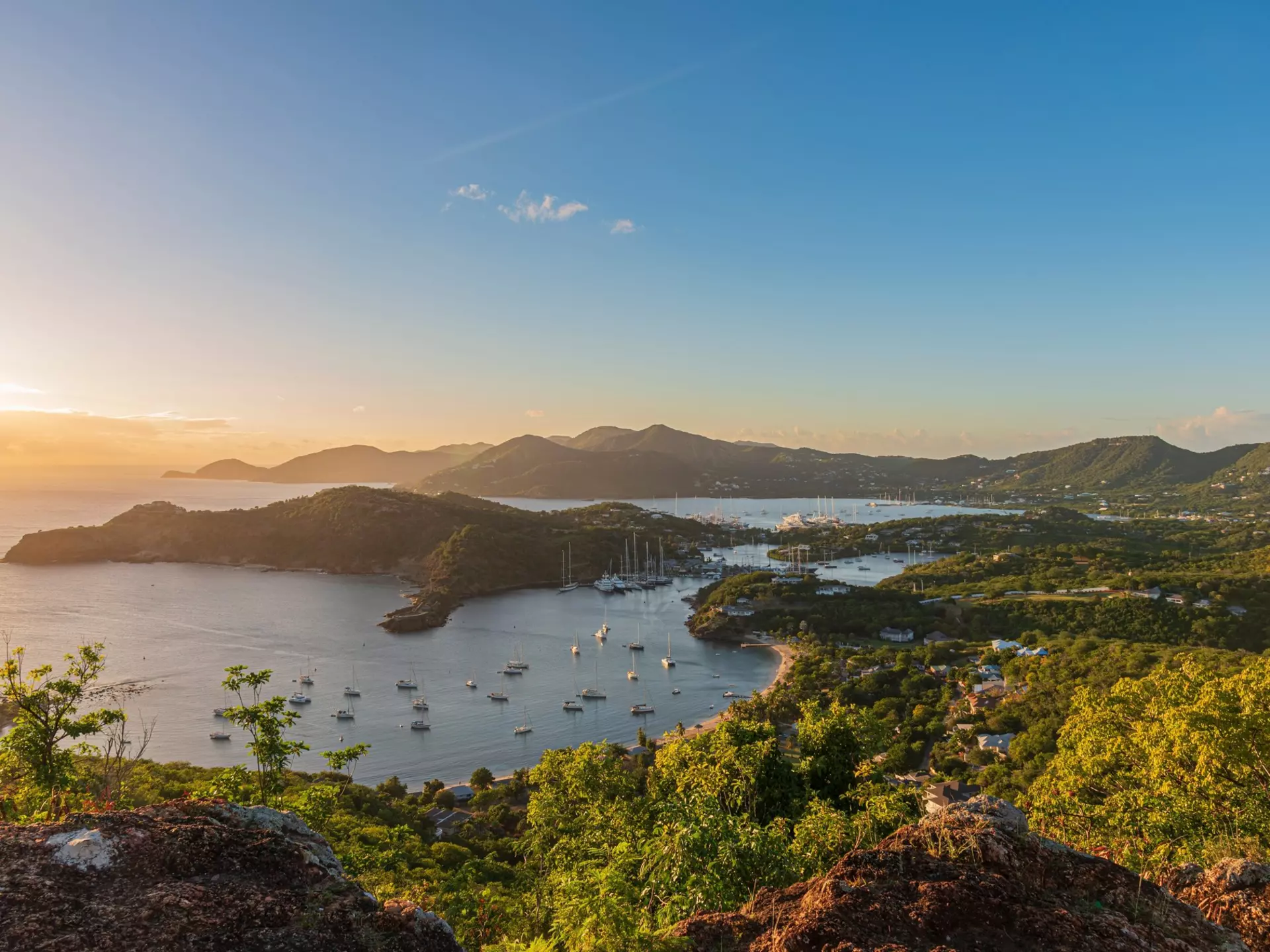 A boat moored in turquoise water by a sandy beach in Puerto Rico; the hillside is covered with green vegetation, and the sky is blue with white clouds.