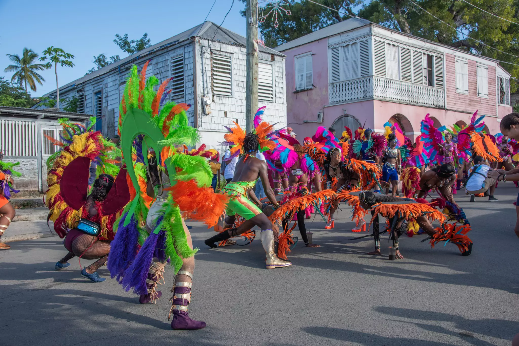 Dancers in feathered costumes perform in the street as part of a festival parade