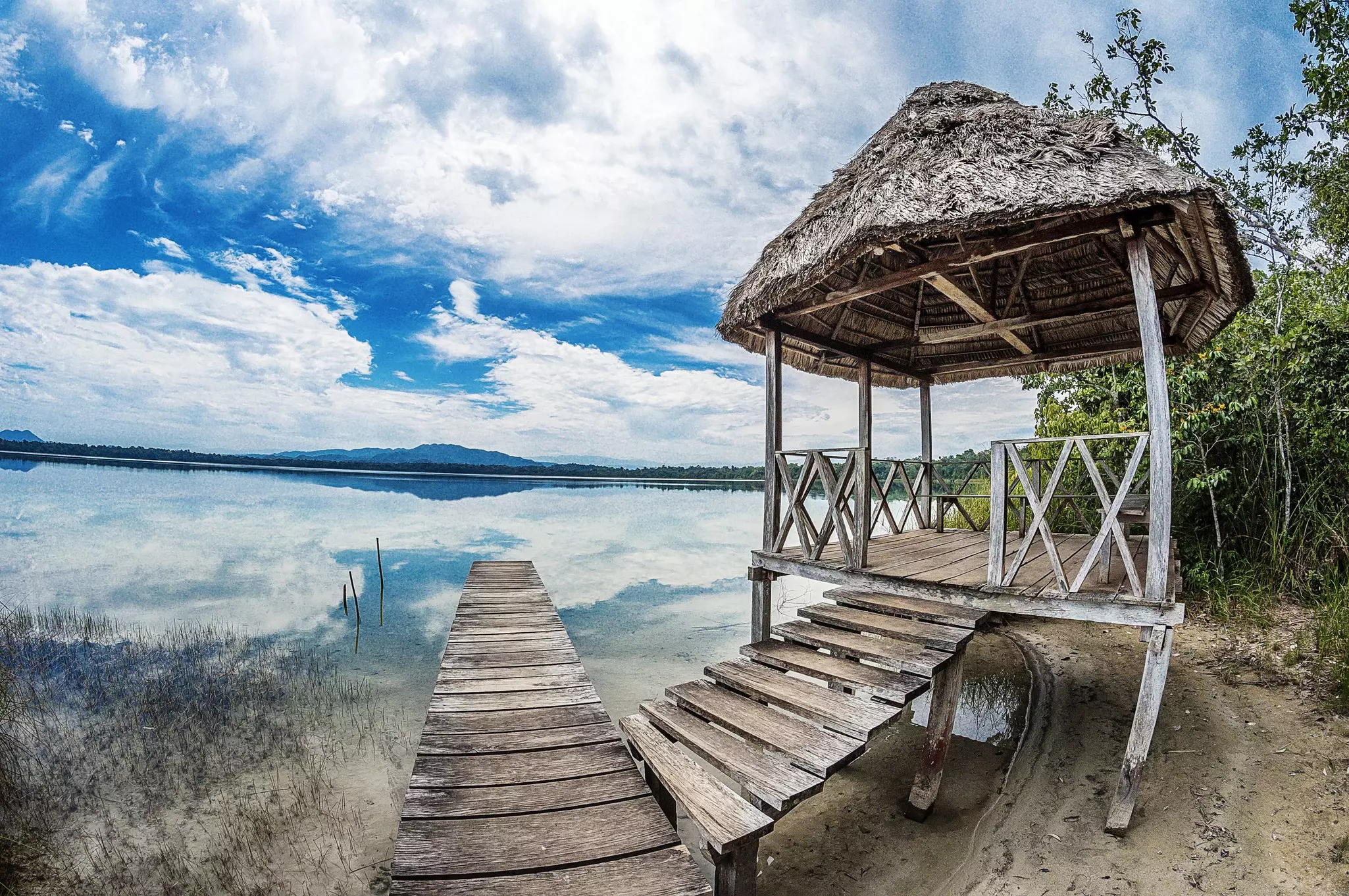 A small wooden structure acting as a sun shade next to a small jetty leading into a lagoon.