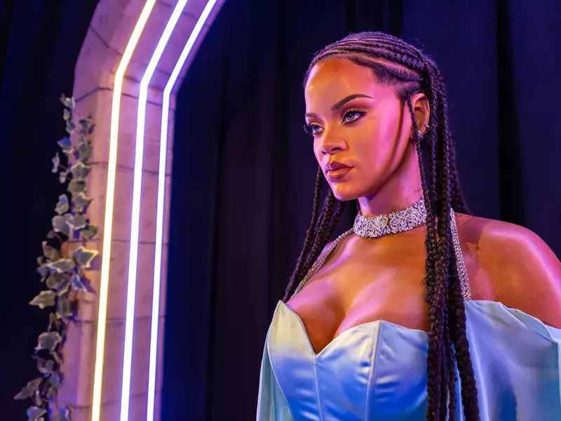 Close-up of singer in individual braids, choker necklace and blue sleeveless dress