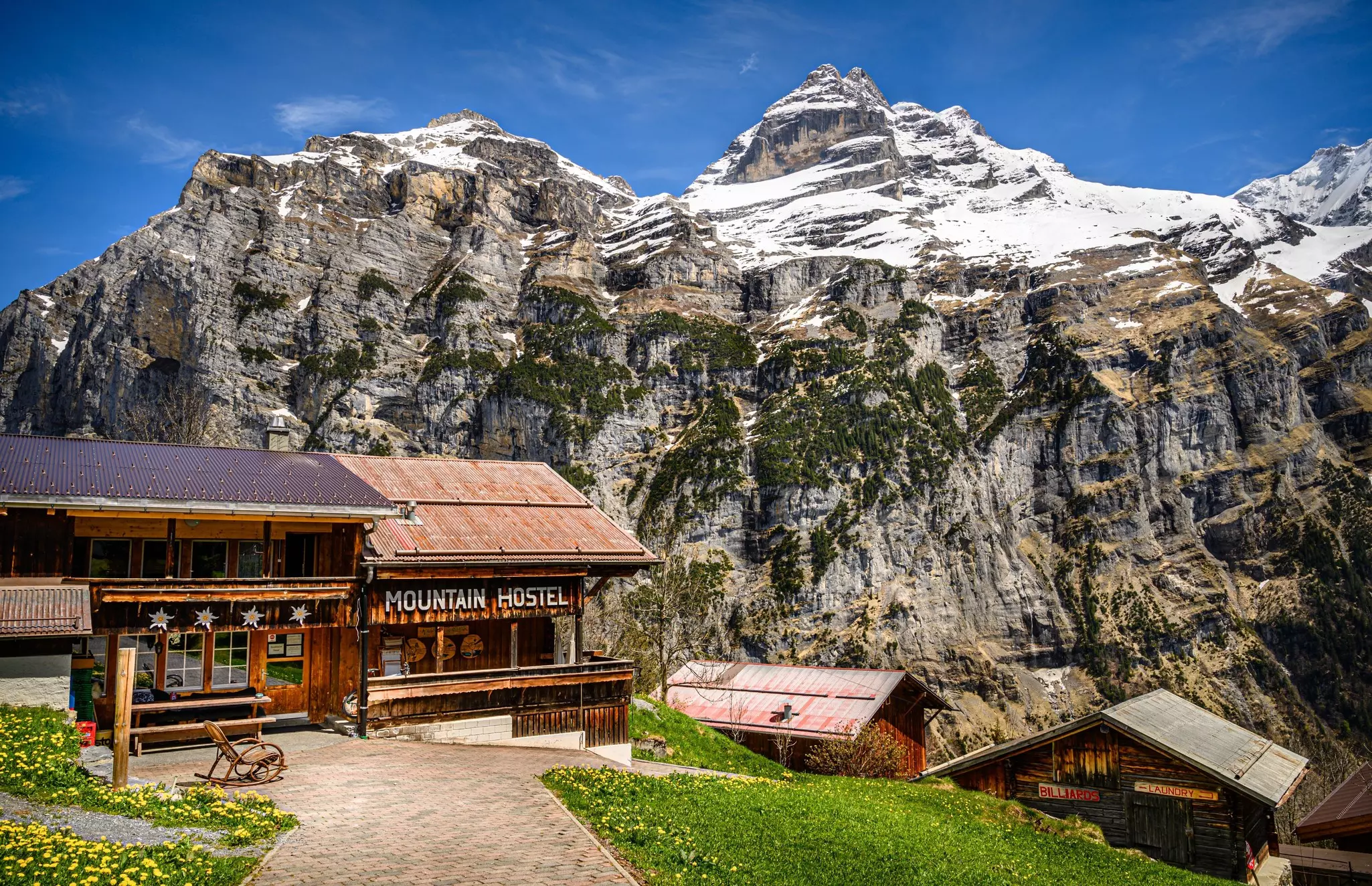 A small mountain hostel in Bernese Oberland with grass in the foreground and mountains in the background.