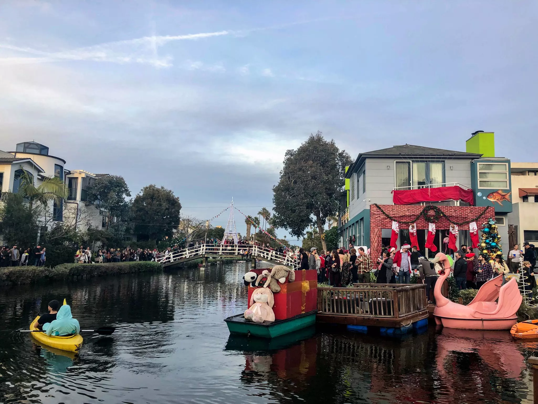 People admire the Christmas decorations on buildings along the edge of a canal.
