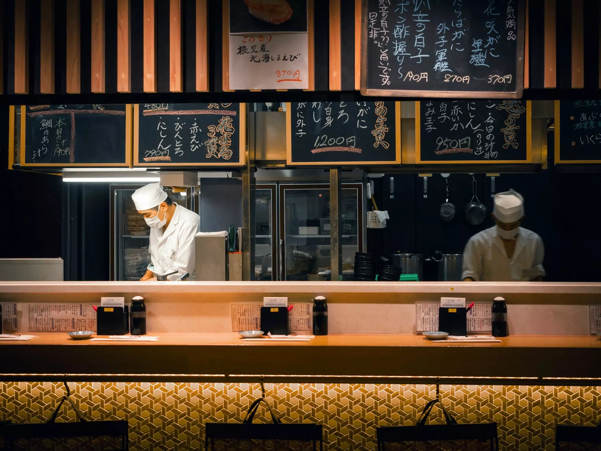 Two chefs preparing food behind a counter in a restaurant