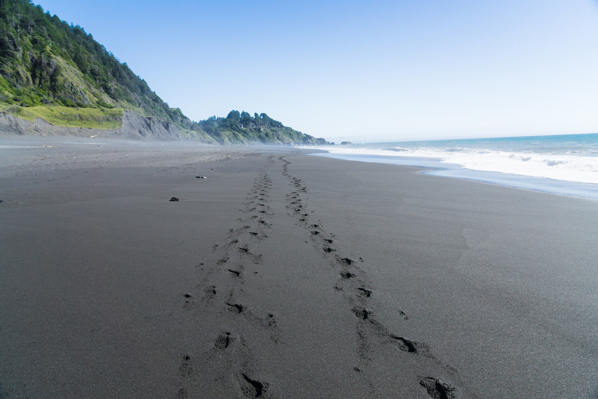 Footsteps in the black sand of the Lost Coast backpacking trail in California.