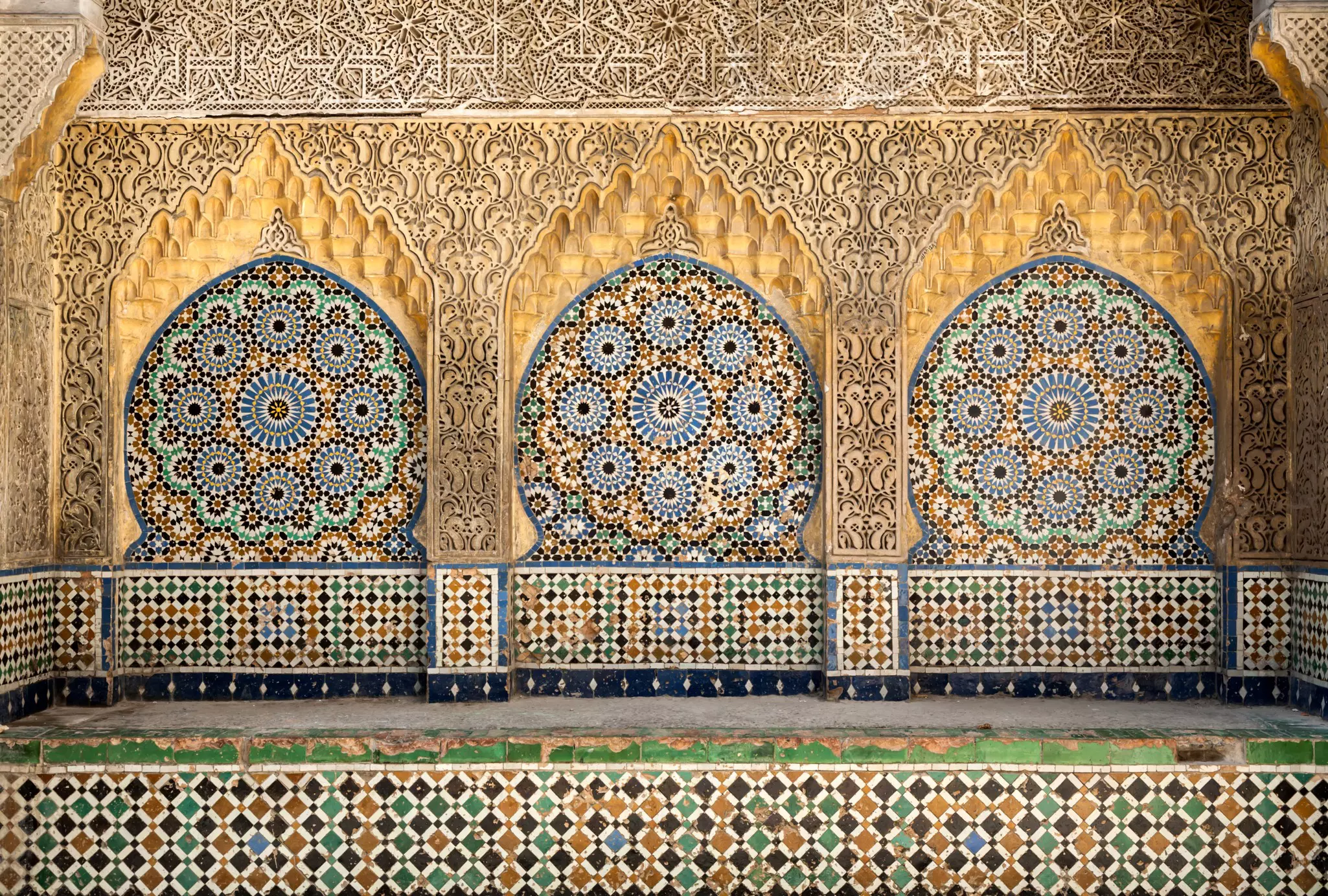 An alcove in the Kasbah, Tangier, tiled with ornate blue and yellow tiles and decorated with carved stone.