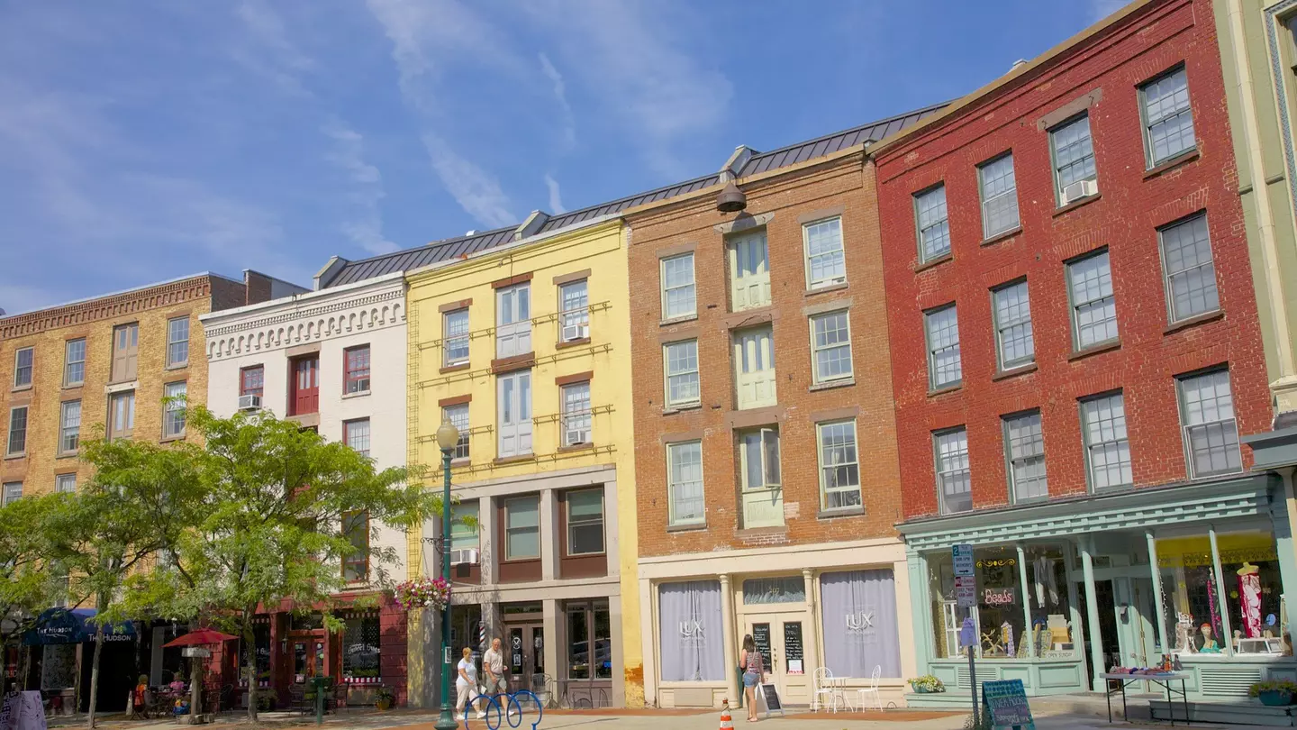 A few people walk in front of the colorful facades on curved street of Antiques Row on River Street in downtown Troy.