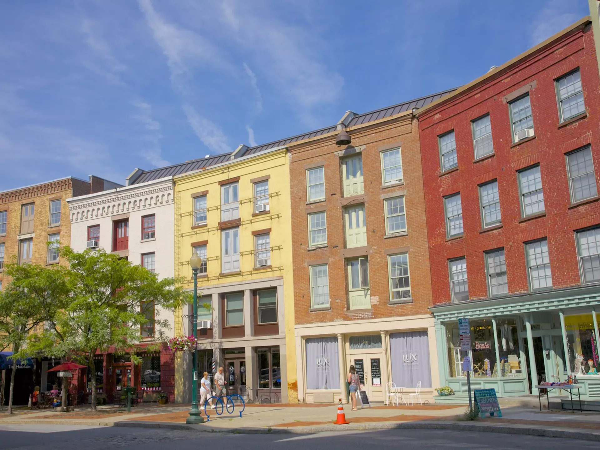 A few people walk in front of the colorful facades on curved street of Antiques Row on River Street in downtown Troy.
