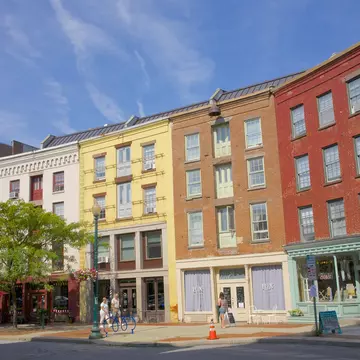 A few people walk in front of the colorful facades on curved street of Antiques Row on River Street in downtown Troy.