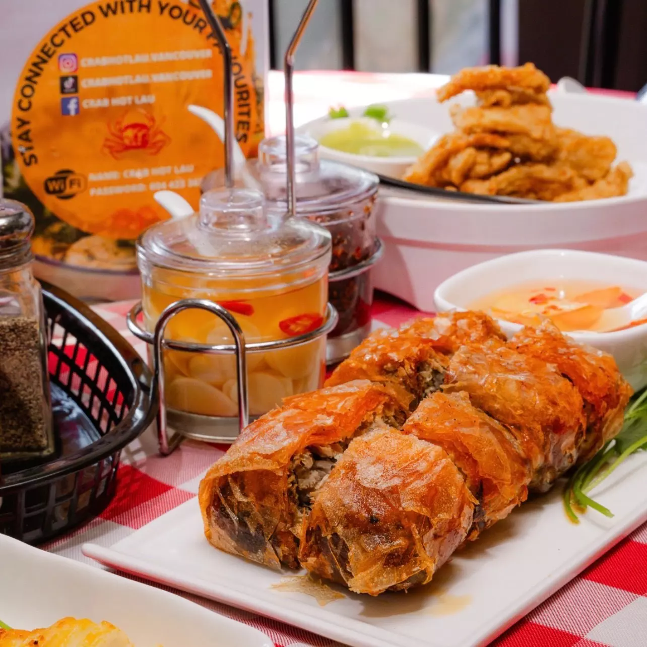 A table packed with dishes, including a roll with flaky pastry, and condiments.