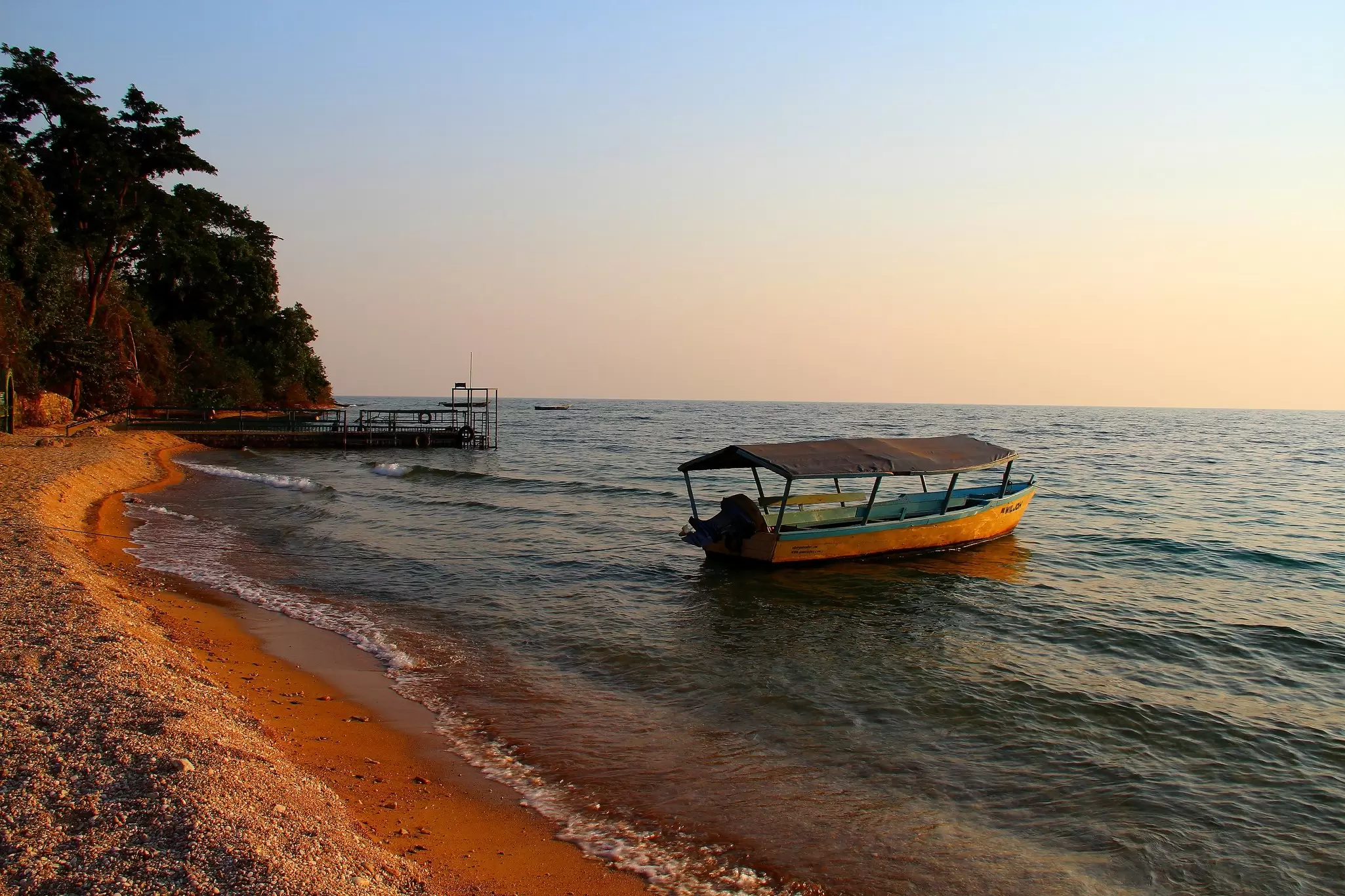 A boat is moored off the shore at sunset in Lake Tanganyika in Gombe National Park, Tanzania